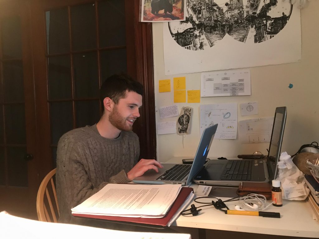 alternative studying Student sitting at a desk with two laptops in front of him