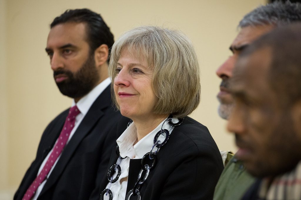 Theresa May sits between three men