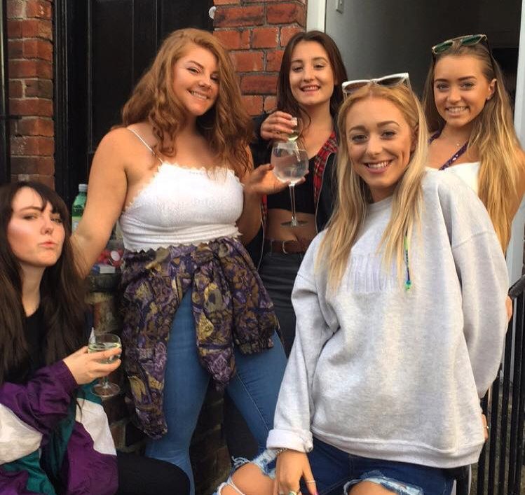 A group of friends stand outside their front door