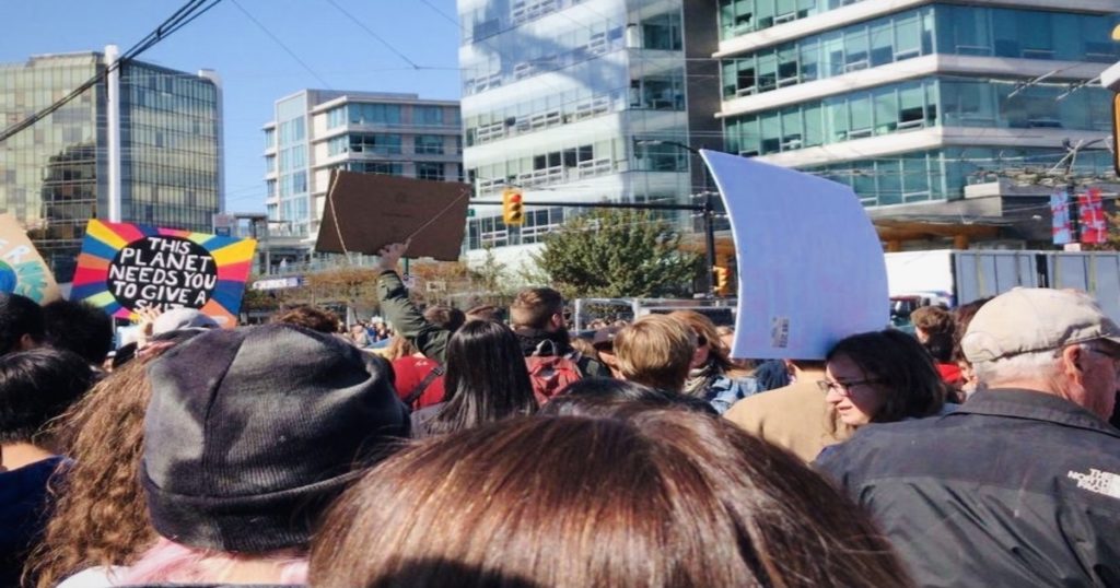 Horizontal photo of a climate protest within a crowd of people holding signs