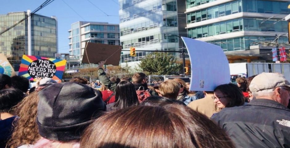 Horizontal photo of a climate protest within a crowd of people holding signs