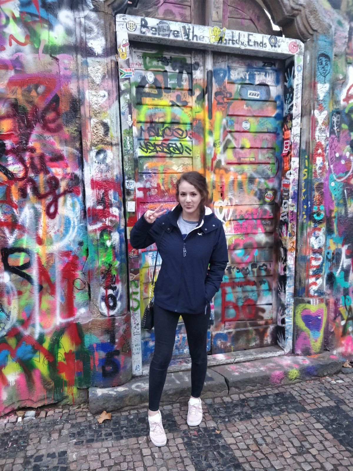 Image may contain: Overcoat, Coat, Female, Path, Walkway, Pants, Wall, Painting, Art, Mural, Graffiti, Human, Person, Footwear, Apparel, Shoe, Clothing