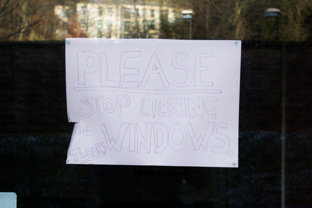 An A4 sign reads: 'PLEASE STOP LICKING THE WINDOWS'.