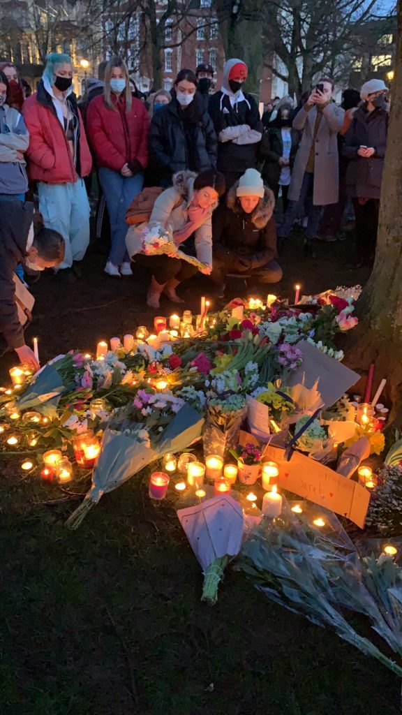 crowds gathered for a vigil for Sarah Everard on college green with flowers and candles