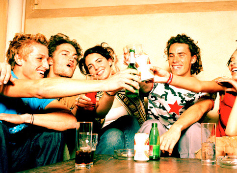 Portrait of a group of young men and women holding drinks in a bar