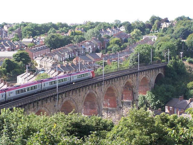 Image may contain: Hedge, Fence, Vase, Pottery, Potted Plant, Plant, Jar, Flora, Vehicle, Transportation, Train, Viaduct, Building, Bridge