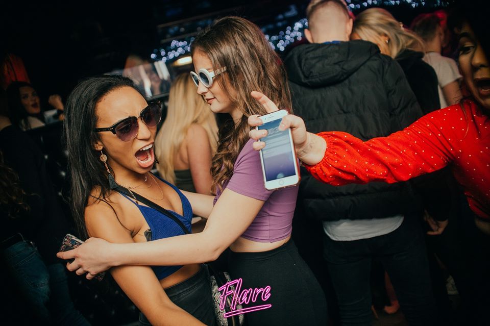 Image may contain: Night Club, Party, Club, Night Life, Electronics, Mobile Phone, Phone, Cell Phone, Accessories, Sunglasses, Accessory, Person, Human