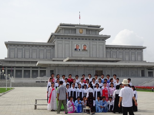 A group of villagers posing with the Kumsusan Palace of the Sun
